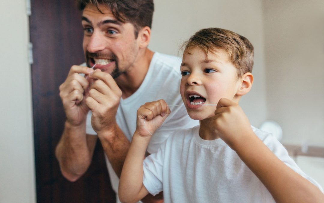 dad with his child flossing their teeth in the mirror